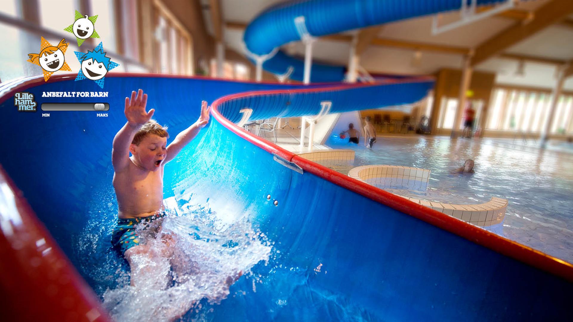 Gutt leker i vannsklie på Jorekstad Fritidsbad