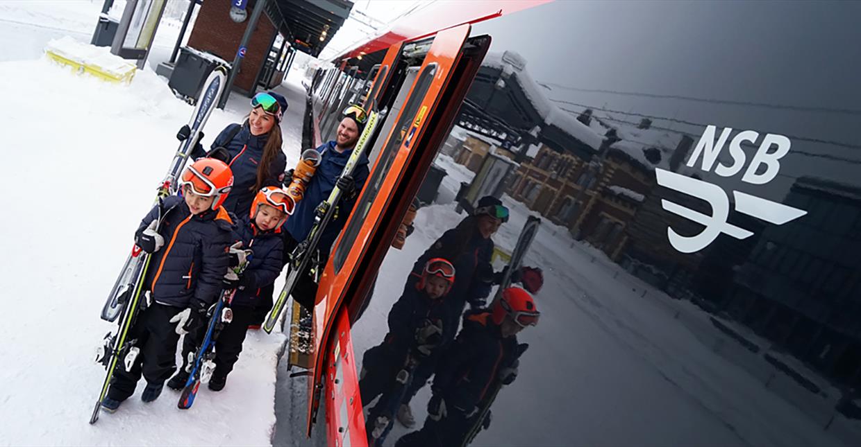 Familie med alpine ski går av toget på togstasjonen