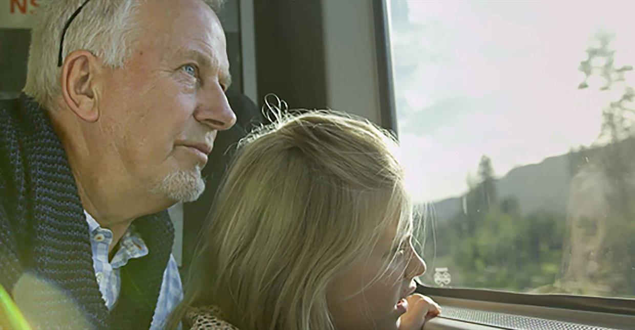 Grandparent and child looking out the window of a train