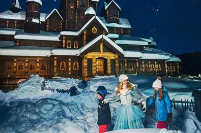 Prinsessa i Hunderfossen utenfor eventyrslottet med to barn i vinterparken