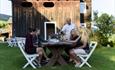 Gjester nyter et glass vin rundt et bord ute på tunet på Sygaard Grytting