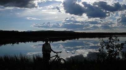 Man standing beside his bike enjoying the view over the Jetningen lake. 
