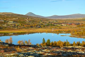 Overview of the area around the hotel with mirror lake, mountains and fall colors. Spidsbergseter Resort Rondane.