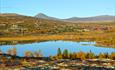 Overview of the area around the hotel with mirror lake, mountains and fall colors. Spidsbergseter Resort Rondane.