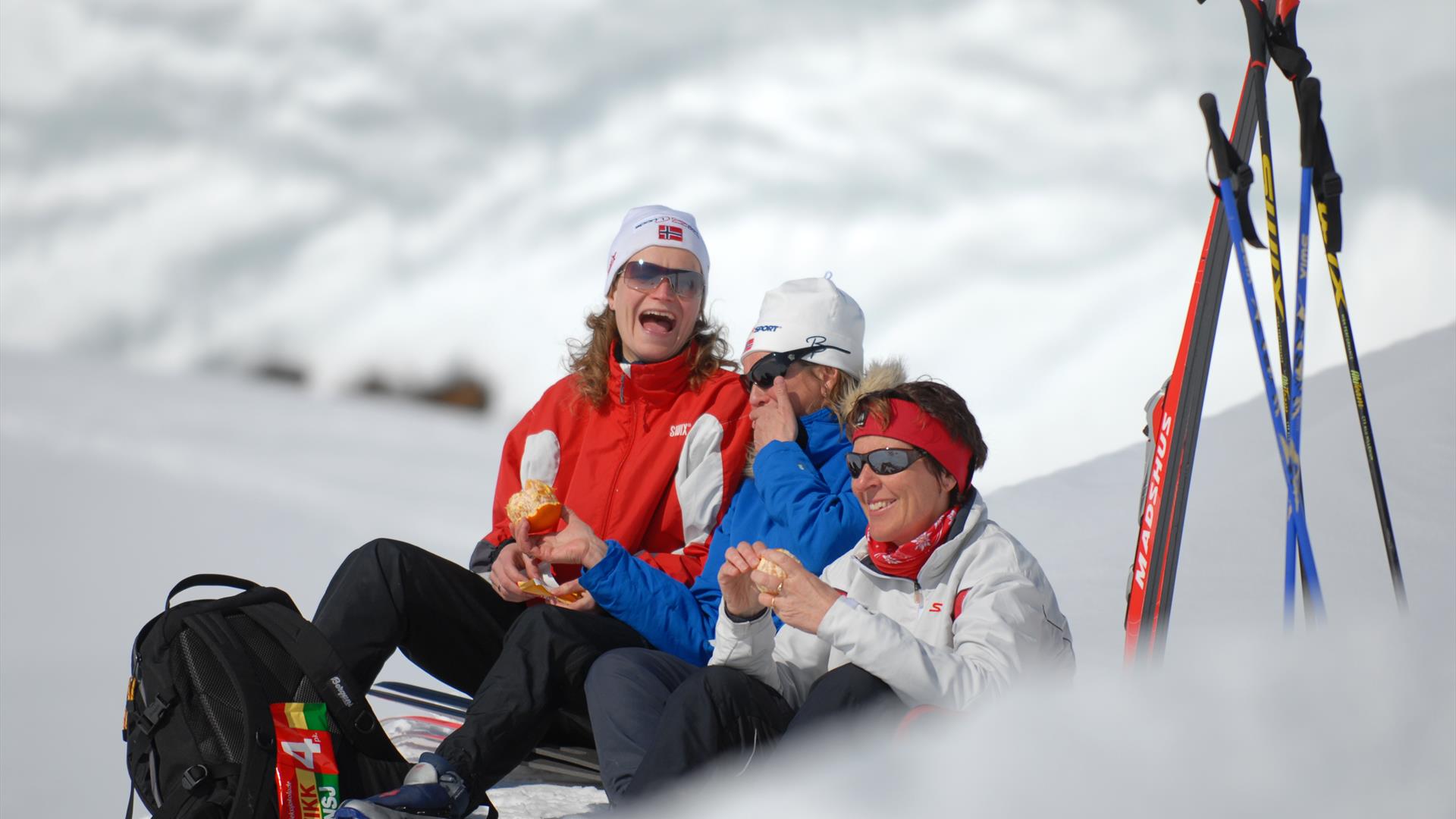 blide damer koser seg med appelsin og sjokolade på skitur