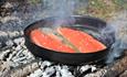 Two trout are fried in a fire pan.
