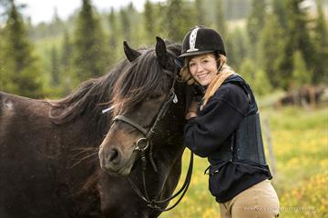 A young woman smiles towards the camera with her horse