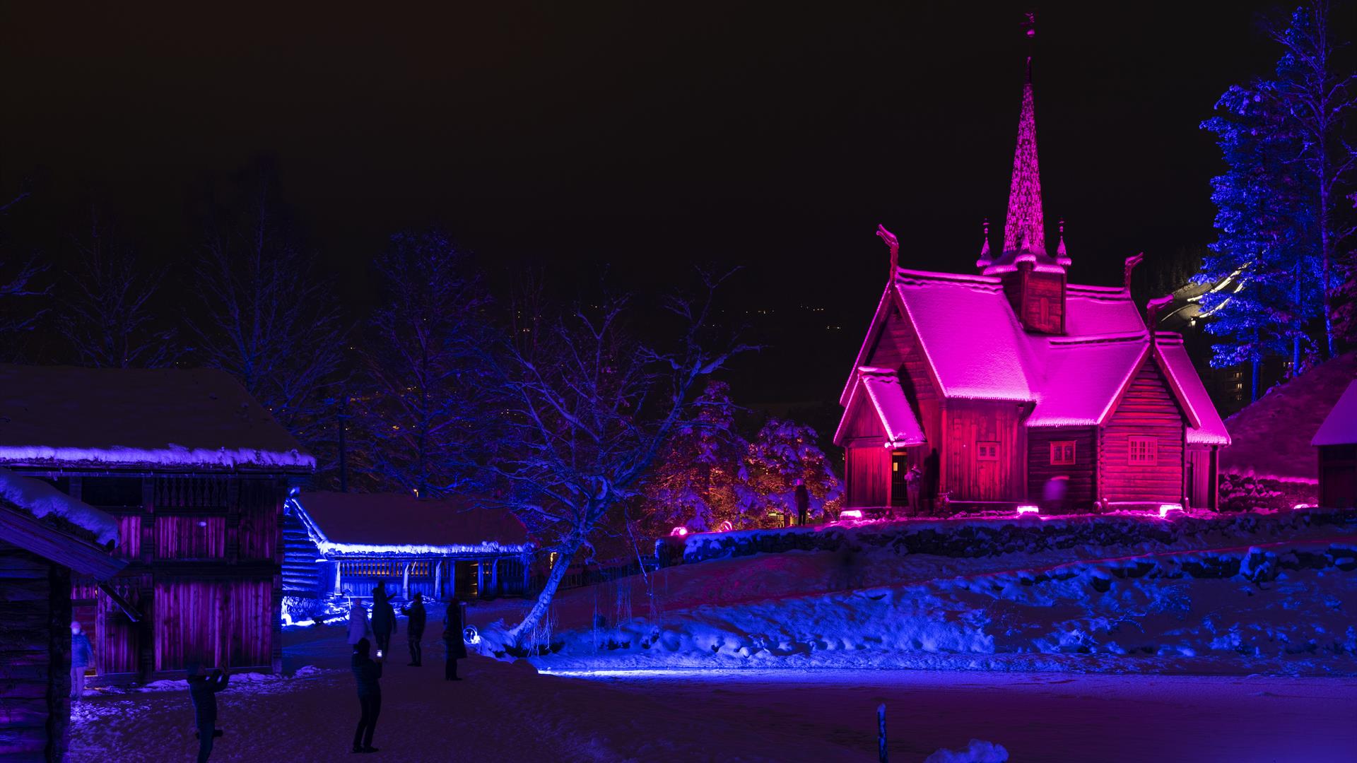 Garmo stavkirke lyssatt i rødt lys en vinterkveld.
