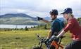 Two mountainbikers enjoying the view over a mountain lake.