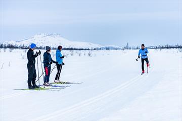 Skigåere ser på instruktøren som demonstrerer skiteknikk i skisporet.