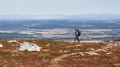 Person walking along a mountain ridge with views of valley and water