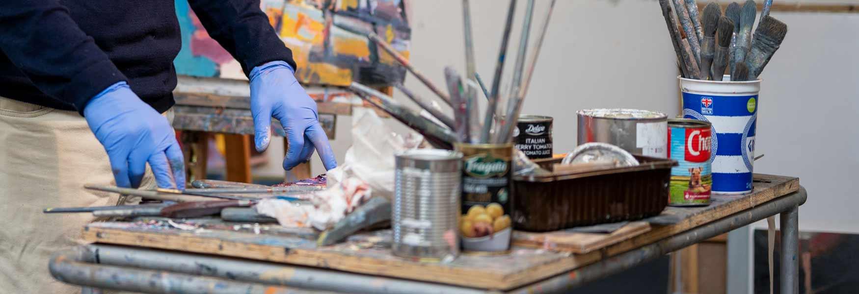 A busy creative desk with arms showing