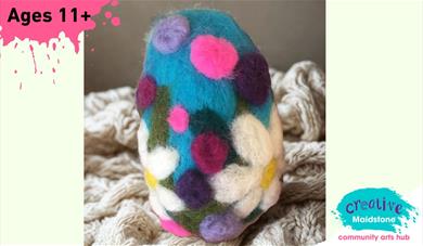Needle-felted Easter Egg sitting on a woollen blanket on a yellow background