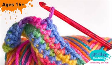 Crochet hook with a brightly coloured ball of yarn and a small piece of crochet work