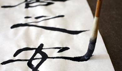 Calligraphy brush making Chinese characters on white paper