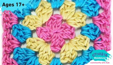 A crochet granny square made with pink, yellow and blue yarns