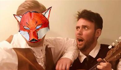 Two performers dressed as Brothers Grimm with a paper animal mask covering the face of one