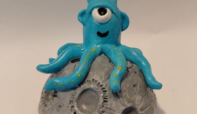 Picture of a blue alien with tentacles on a small moon