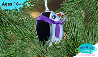 Handmade stained glass penguin tree ornament, hanging in a Christmas tree
