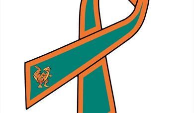 Green and orange ribbon with the ends folded over and a dinosaur on one end