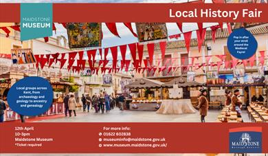 A medieval market, outdoors, with red bunting hanging across buildings, and vendors interacting with the public. There are cobbled stones on the walkw