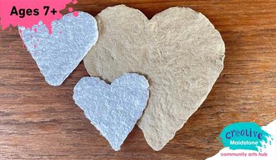 Three heart-shaped pieces of handmade paper on a wooden background