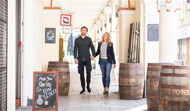 A couple walking through the covered walk way in Market Buildings