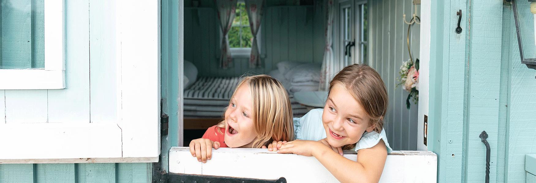 Two girls looking over the door of the shepherds hut at Kits Coty Glamping.  This Award Winning glamping site has a proven track record in delivering outstanding customer care.