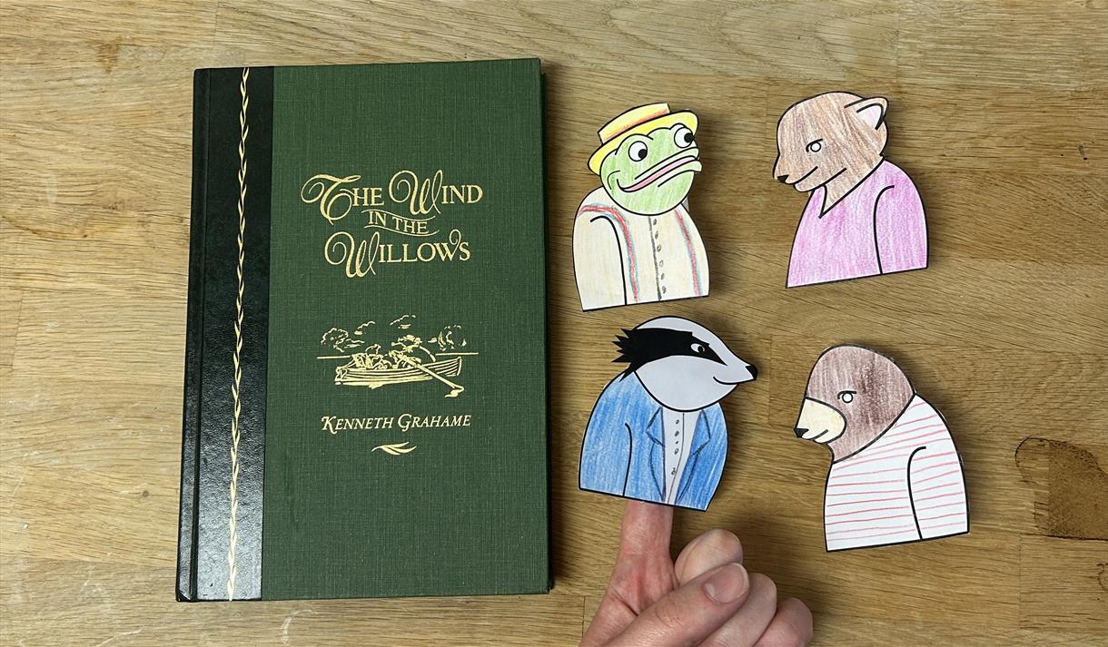 a book cover of "Wind In the Willows" with finger puppet of Toad, Ratty, Badger and Mole