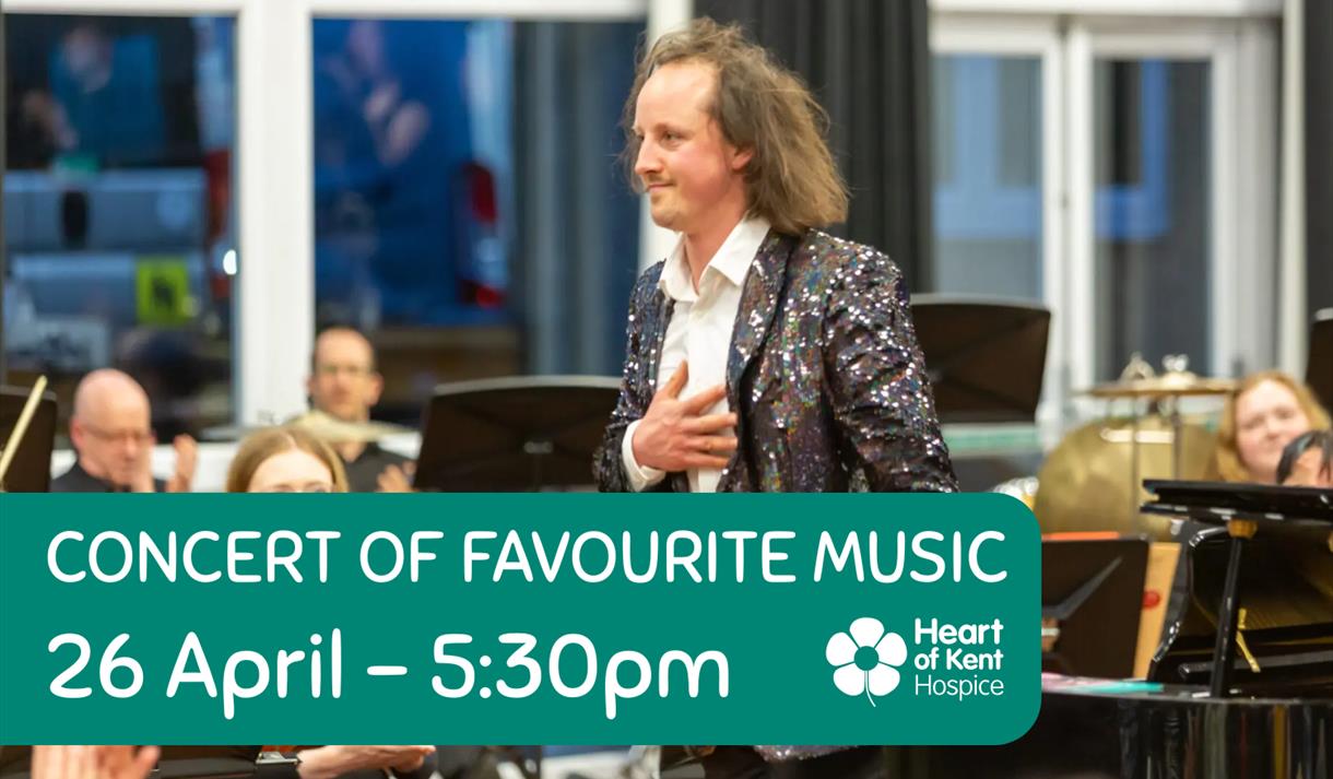 Conductor standing at front of orchestra taking applause