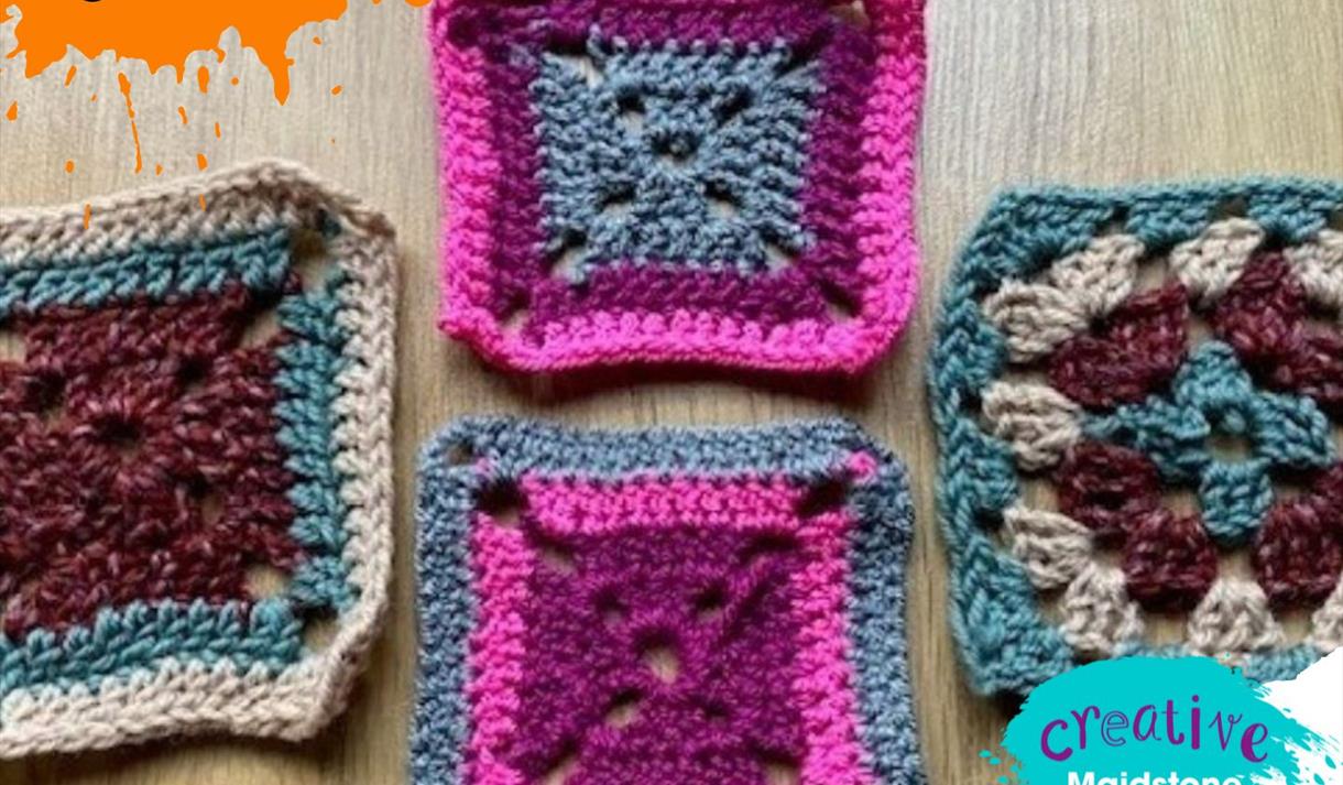 Four crocheted granny squares in various colours on a wooden background