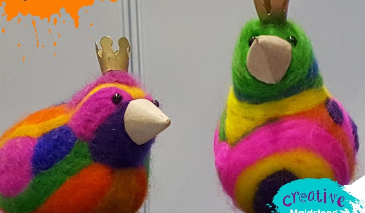 Two brightly coloured needle-felted birds with cardboard beaks and paper crowns