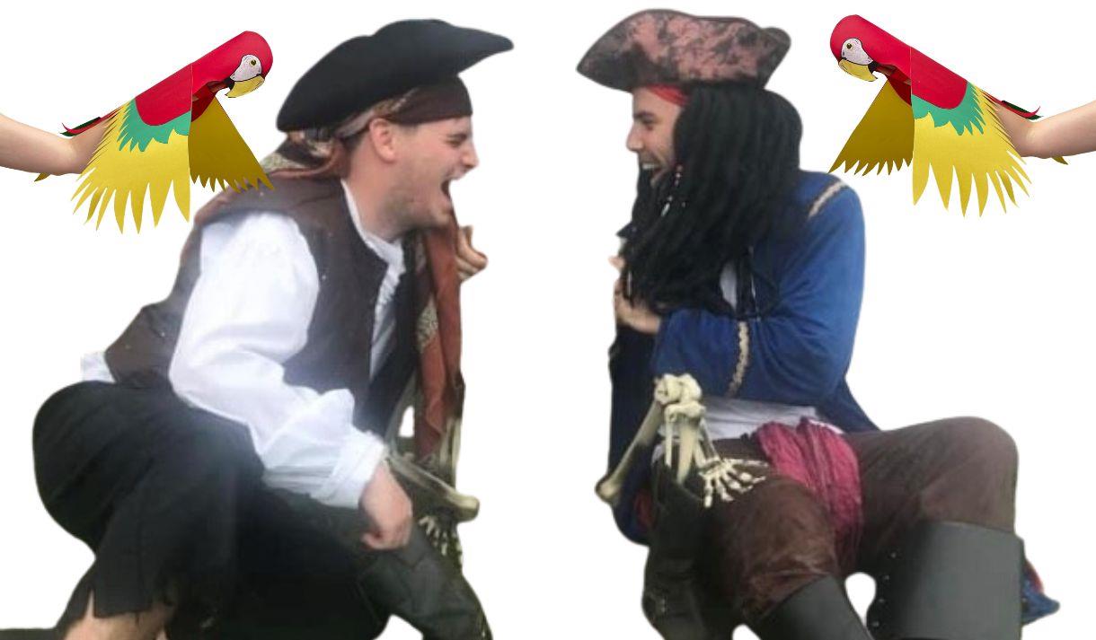 Two characters dressed as pirates sat opposite each other. Two paper parrot puppets flying over their shoulders
