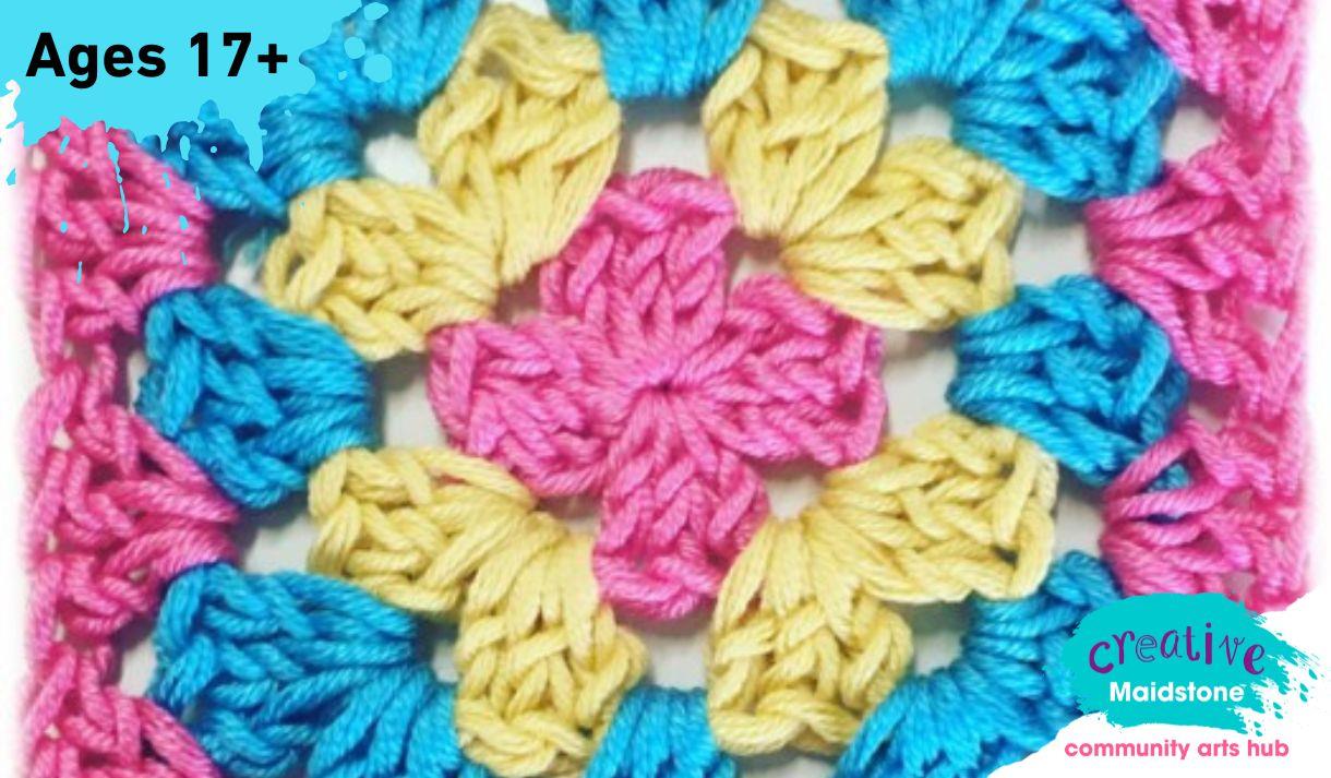 A crochet granny square made with pink, yellow and blue yarns