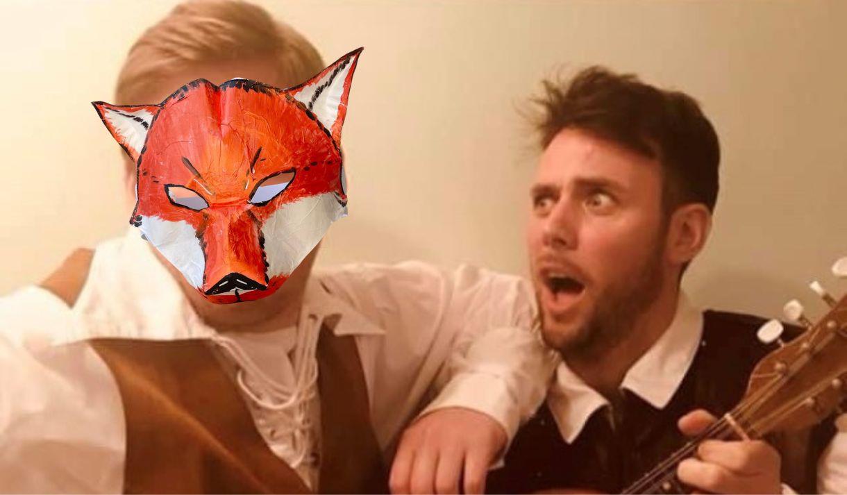 Two performers dressed as Brothers Grimm with a paper animal mask covering the face of one