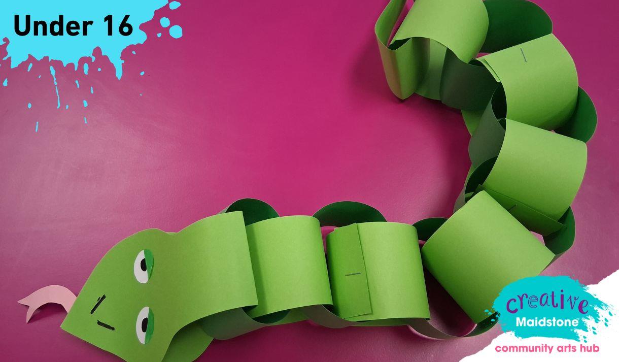 Green paper snake on a pink background