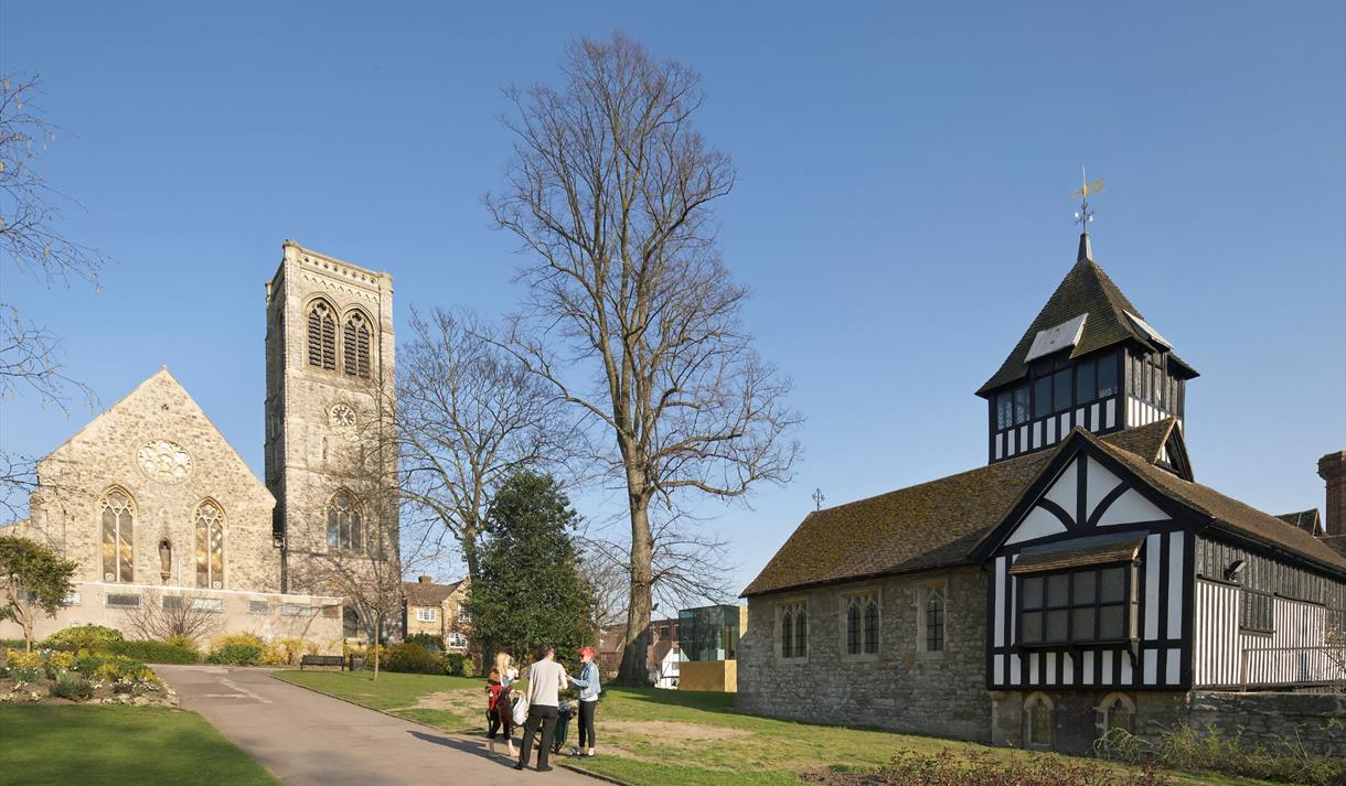 A group of people in Brenchley Gardens, Maidstone with the museum and St Faith's Church