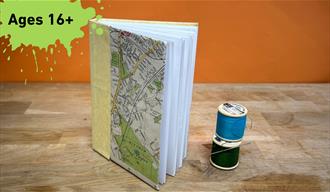 Paint splat with the words Ages 16+ main image a book with 2 cotton reel next to it