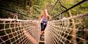 Woman walking through net on high ropes