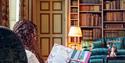 Lady sitting in armchair reading in the Castle library