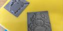 Two laser cut stamps on a yellow background. One of Picachu, the other of a crab