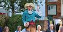 A performer motions expressively as audience members look on.