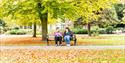 People sitting on park bench in Brenchley gardens in Autumn