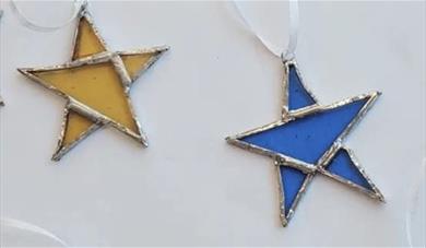 Two stained glass stars, one yellow and one blue on a white background