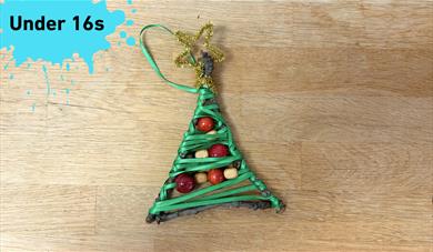 Under 16s with pain splat. main image: a small ornament in the shape of a tree made with ribbons, sticks, and beads.