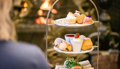 Afternoon tea at the Chilston Park cakes displayed on a 3 tiers stand in front of the fire.