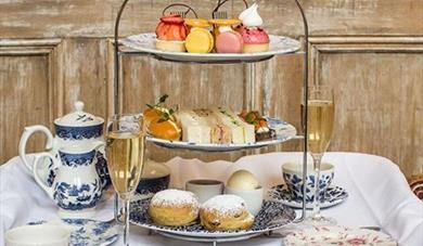 Afternoon tea on three tier stand with champagne glasses and tea pot