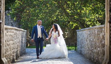Bride and groom walking hand in hand at Leeds Castle