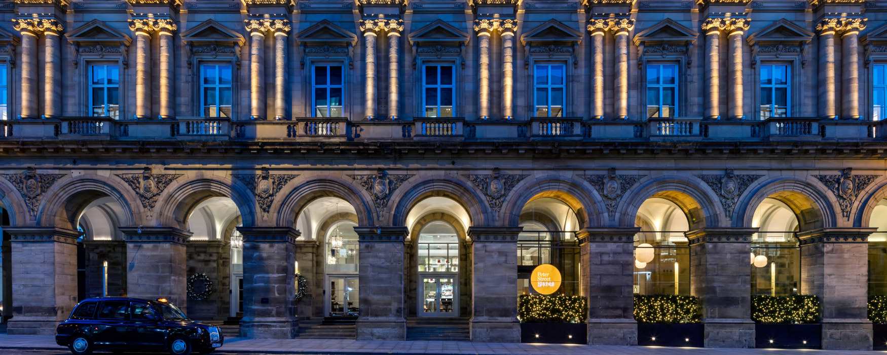 A taxi in front of a grand historic hotel