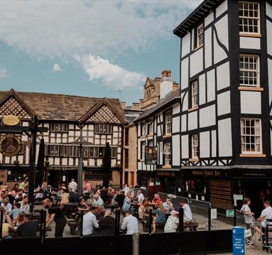 People sat in a square outside Tudor building